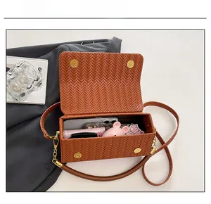 Macro shot of brown woven leather box bag showing interior storage and magnetic closures