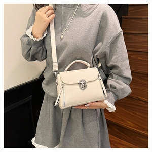 Detailed view of cream leather handbag with silver twist lock and lychee grain texture