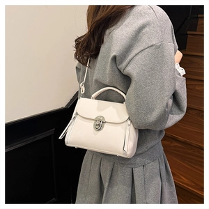 Detailed view of cream leather texture with silver metal clasp and vertical zippers