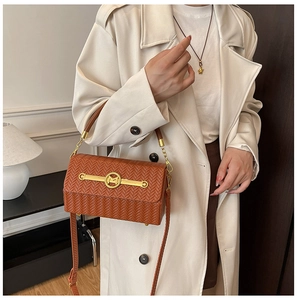 Detailed view of brown woven texture handbag featuring a gold M logo buckle and metal trim