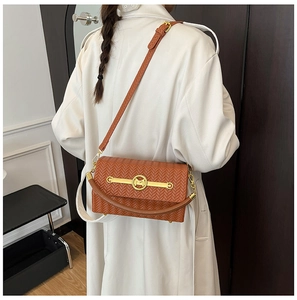 Detail of brown woven shoulder bag featuring a circular gold M buckle and fine texture