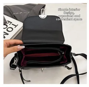 Detail view of the black crossbody bag's multi-compartment interior and burgundy lining