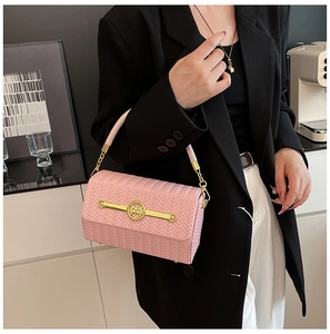 Macro detail of pink woven texture on a structured handbag with a gold M-shaped metal clasp