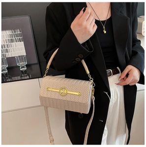 Detailed close-up of beige woven texture bag with gold M-logo and adjustable strap