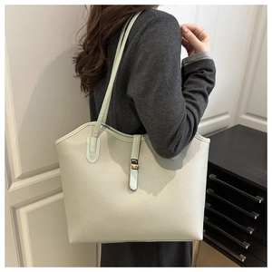 Detailed view of light green pebbled leather tote bag worn by a model on the shoulder