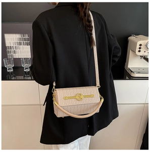 Detail of beige woven texture shoulder bag with gold M-logo and elegant crossbody strap