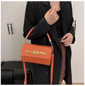 Detail of orange woven box bag featuring gold M-buckle and metallic chain strap