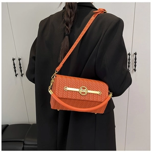 Detail of orange woven crossbody bag showing luxury texture and golden M letter buckle