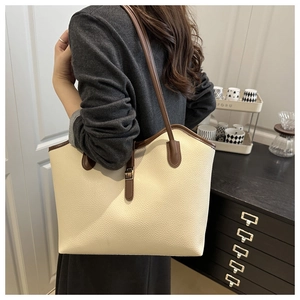 Detail of cream pebbled leather tote with brown trim and gold metal buckle closure
