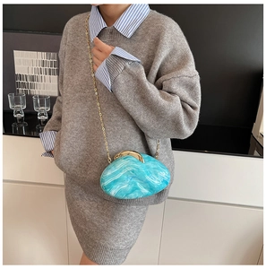Detail of light blue marble textured acrylic shell bag with elegant gold chain strap