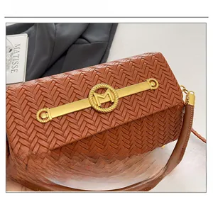 Detail of woven brown leather texture and gold M logo hardware on luxury crossbody bag