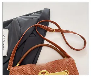 Detail view of woven brown leather handbag featuring gold clasp and adjustable strap
