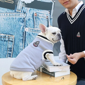Detail of preppy knit pet vest with contrast stripes and crest embroidery on wooden table