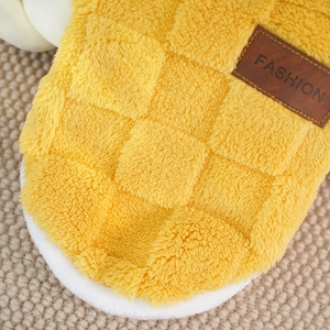 Macro detail of yellow plush slipper with checkered texture and fashion leather tag