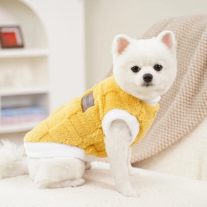 Close-up of yellow quilted plush pet vest with white fleece trim and fashion label
