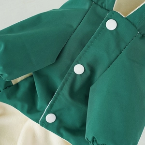 Close-up of windproof dark green fabric with warm white fleece lining and resin buttons