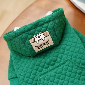 Detail eines grünen gesteppten Haustier-Hoodies mit Bären-Patch und Rautenmuster
