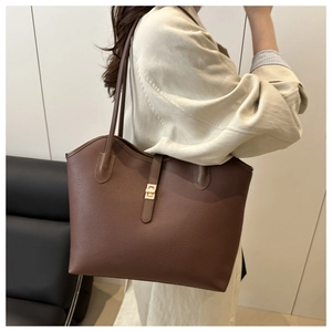 Detail view of lychee texture leather and gold metal lock on dark brown tote bag