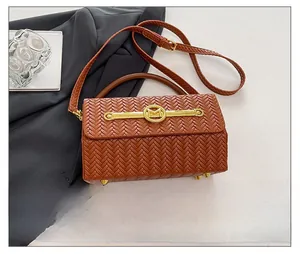 Detail of woven brown handbag featuring a gold M-shaped metal buckle and premium texture