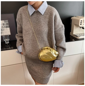 Detail of a gold mirror-finish pebble-shaped acrylic evening bag with a metal chain