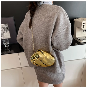 Detail of a modern golden metallic shell evening bag with a sleek fluid ripple surface