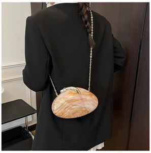 Detail of orange marble acrylic clutch bag with gold chain strap on black blazer