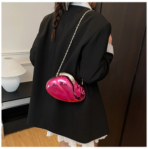 Pink heart-shaped acrylic evening bag with gold chain strap shown on a model