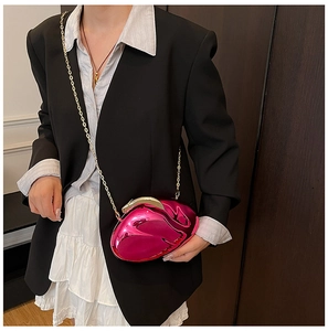Detail of a bright pink round acrylic evening bag with gold chain strap on a black blazer
