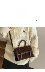 Détail d'un sac bandoulière marron foncé vintage avec texture suédée et boucles cuir