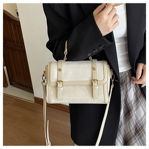 Détail d'un sac bandoulière vintage beige avec boucles dorées et lanières en cuir