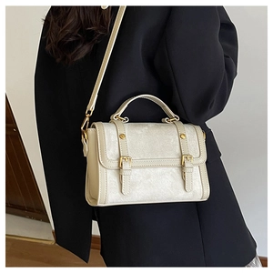 Détail du sac rétro blanc cassé avec boucles dorées vintage et une poignée supérieure