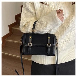 Détail d'un sac cartable noir vintage mat avec boucles dorées et bandoulière réglable