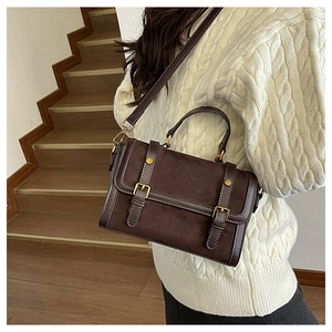 Sac bandoulière rétro marron en matières mixtes porté par un mannequin en intérieur