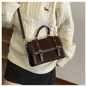 Détail de la sacoche vintage café foncé avec double boucle sur un pull en maille