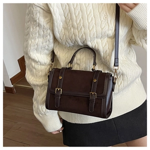 Détail du sac Boston marron mat avec boucles dorées et bandoulière réglable pratique