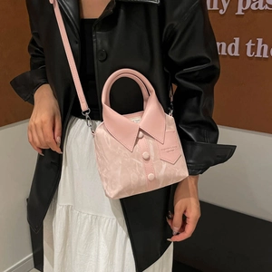 Pink shirt-shaped bucket bag with collar and button details, worn as a crossbody purse
