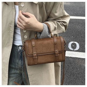 Détail du sac Boston vintage en cuir marron avec surpiqûres mates et boucle dorée