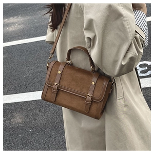 Vue de rue d'un sac à bandoulière marron rétro porté avec un trench-coat beige chic