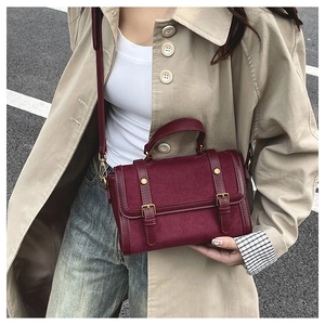Détail du sac vintage bordeaux avec lanières décoratives en cuir et clous en métal doré
