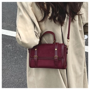 Détail du sac bandoulière bordeaux avec mélange de matières et finitions dorées