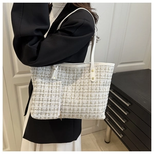 Detail of white tweed tote bag with metallic threads and leather strap with gold rivets