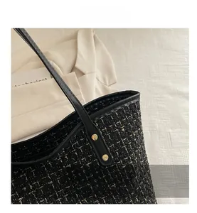Detailed macro of black tweed tote bag featuring leather handles and gold rivet accents