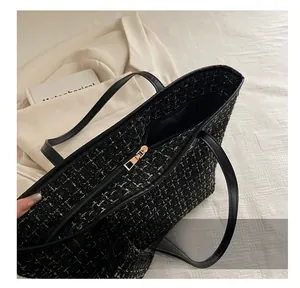 Detailed macro of smooth gold zipper and black-gold tweed weave texture on tote bag