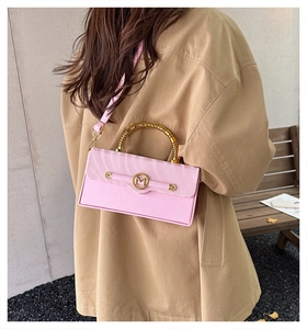 Detailed close-up of pink crossbody bag featuring a golden bamboo handle and M logo