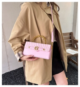 Pink striped handbag with gold bamboo handles and M-shaped metal buckle on a model