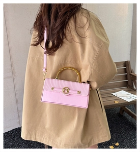 Detailed view of pink leather crossbody bag with bamboo metal handle and M-buckle