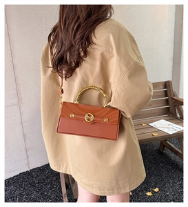 Detail of vintage brown leather handbag with gold bamboo handle and metallic M clasp