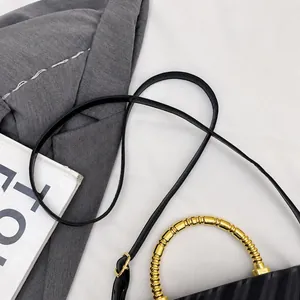 Detail of elegant black textured handbag with golden semi-circular handle and leather strap