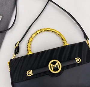 Detail of black leather handbag with gold spiral handle and M-logo metallic ring buckle