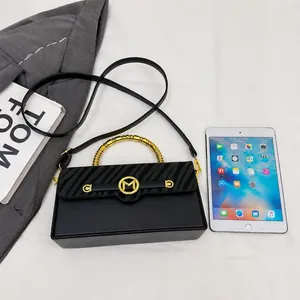 Size comparison of a black flap bag with gold hardware next to a tablet device